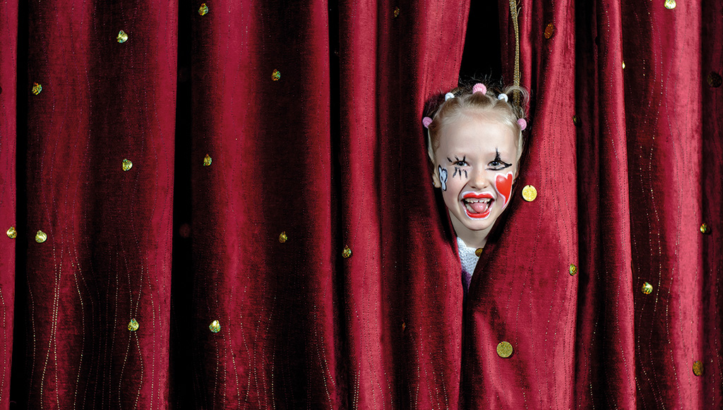 Foto von eines Kindes, das den Kopf durch einen Bühnenverhang steckt